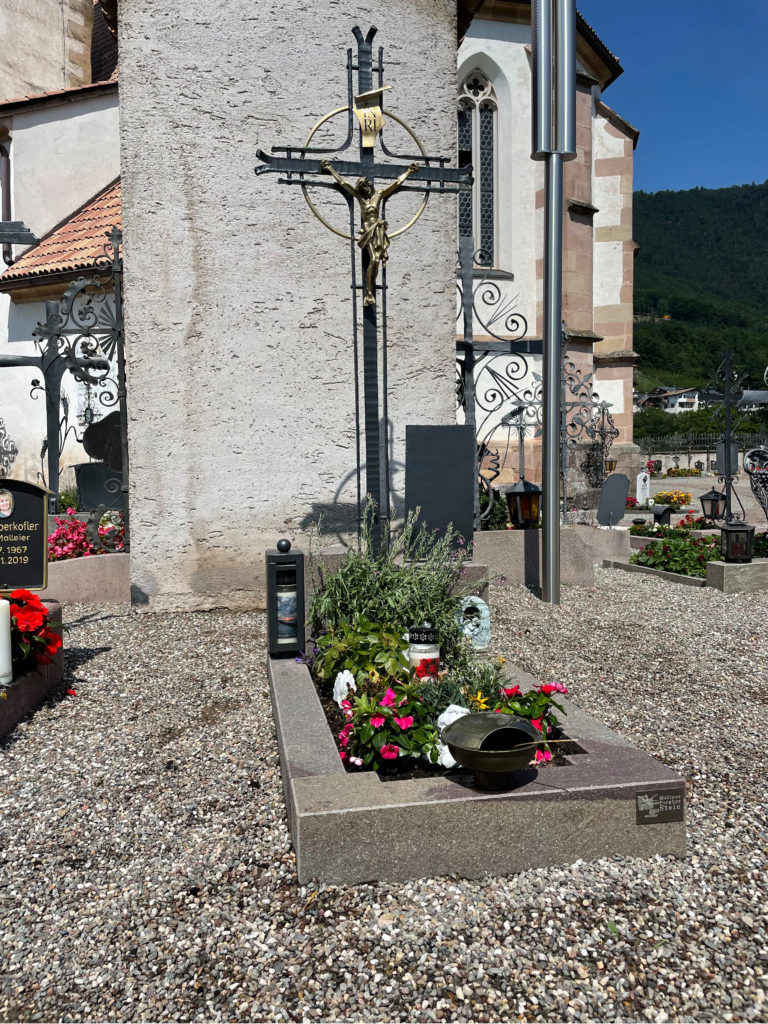 Möltner Porphyr, Bild von dekoriertem Grab, im Hintergrund steht eine Kirche